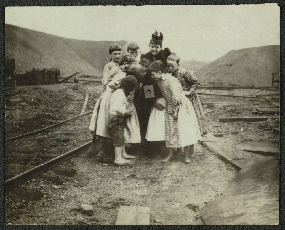 Frances Benjamin Johnston with a group of children looking at her Kodak Brownie camera